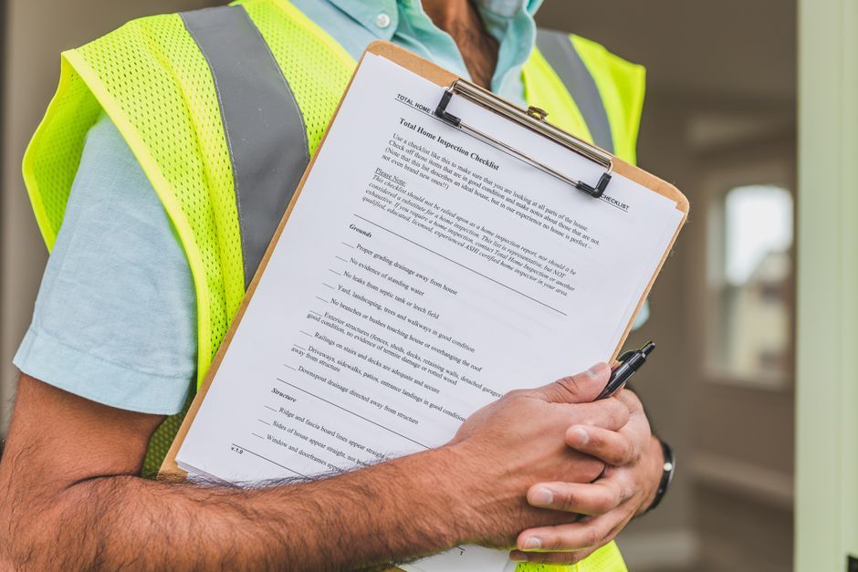 Close-up of home inspector holding a checklist on a clipboard with a pen.