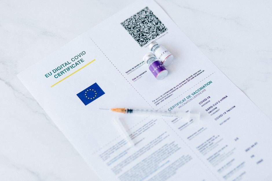 EU digital COVID certificate with vaccine vials and syringe on a white background.